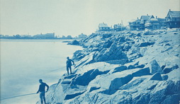 Two Men Fishing from Rocks at Seaside Resort